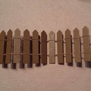 May include: A brown wooden picket fence with wire strung between the pickets.