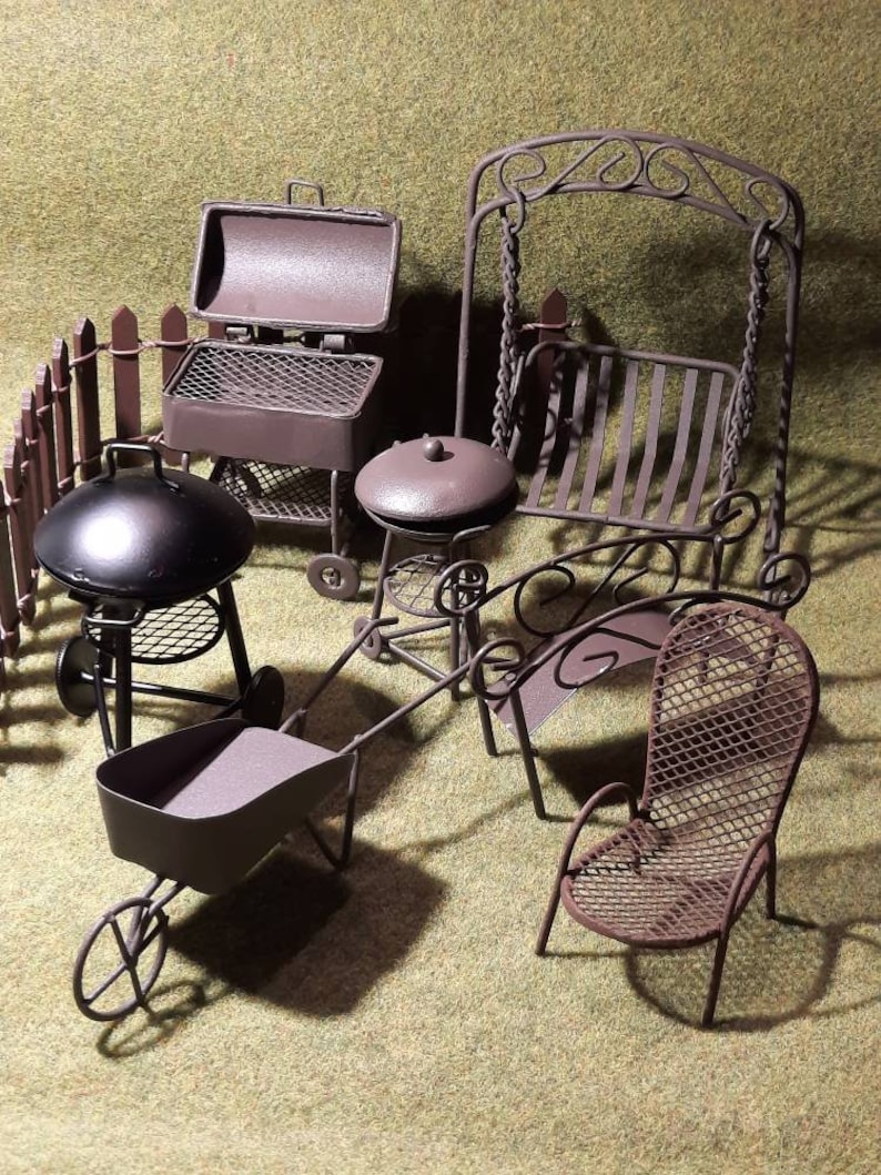 May include: A set of miniature metal garden furniture, including a grill, a swing set, a table and chairs, and a wheelbarrow. The furniture is painted in a brown metallic finish.