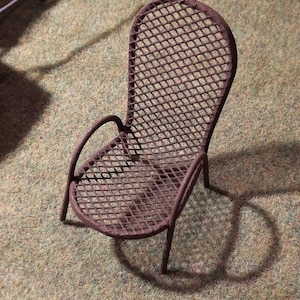 May include: A rusty metal chair with a diamond-shaped wire mesh design. The chair has a curved back and a single armrest.