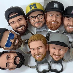 May include: A set of eight bottle openers featuring different male faces with various hairstyles and facial hair. Each opener is made of metal and has a unique design.