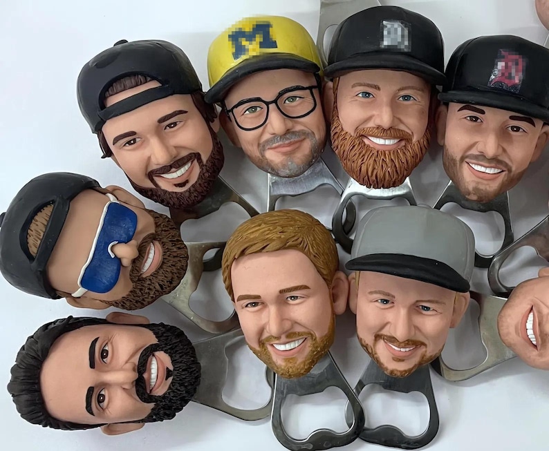 May include: A set of eight bottle openers featuring different male faces with various hairstyles and facial hair. Each opener is made of metal and has a unique design.