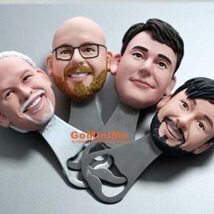 May include: Four personalized bottle openers with 3D sculpted faces. The bottle openers are silver with a black handle and the text "GoMiniMe Wedding Favors &  Bottle Openers" printed on the handle.