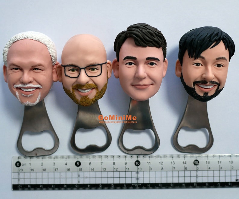 May include: Four personalized bottle openers with different faces sculpted on the top. The bottle openers are made of metal and have a silver finish. The faces are all smiling and have different hairstyles. The bottle openers are arranged in a row on a white surface.