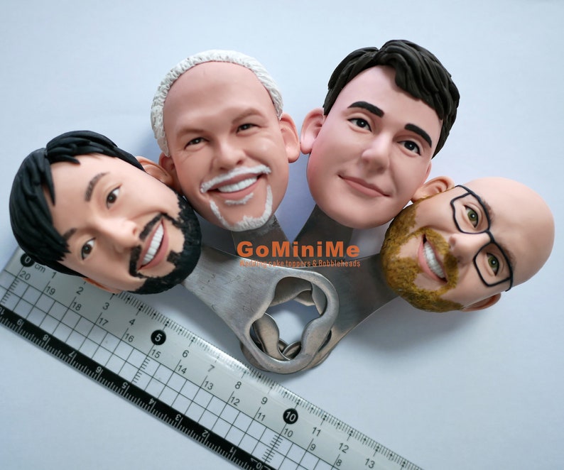 May include: Four custom-made cake toppers, each a realistic portrait of a person's head, are attached to a silver bottle opener. The bottle opener has the text "GoMiniMe" and "Mini cake toppers & Babbleheads".