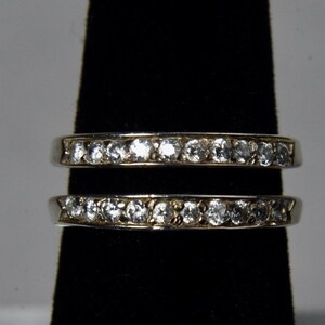May include: Two silver rings with a row of clear cubic zirconia stones on each band.