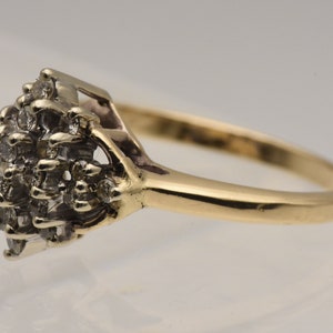May include: A gold ring with a cluster of small diamonds set in a diamond-shaped design.