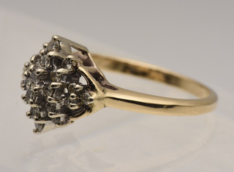 May include: A gold ring with a cluster of small diamonds set in a diamond-shaped design.