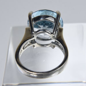 K&ouml;nnte beinhalten: Ein silberner Ring mit einem gro&szlig;en, hellblauen Edelstein, der in einer Krappenfassung sitzt. Der Ring befindet sich auf einem wei&szlig;en Hintergrund.
