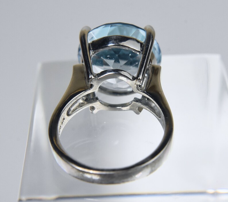 K&ouml;nnte beinhalten: Ein silberner Ring mit einem gro&szlig;en, hellblauen Edelstein, der in einer Krappenfassung sitzt. Der Ring befindet sich auf einem wei&szlig;en Hintergrund.