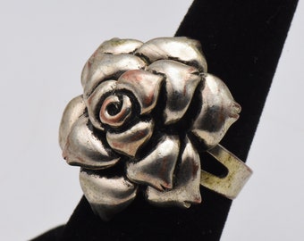 Könnte beinhalten: Ein silberner Ring mit einem Rosenmotiv. Die Rose besteht aus vielen Blütenblättern und hat eine detaillierte Mitte.