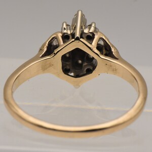 May include: A gold ring with a cluster of diamonds set in a hexagonal shape. The ring is set with a total of 10 diamonds.