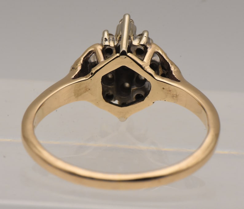 May include: A gold ring with a cluster of diamonds set in a hexagonal shape. The ring is set with a total of 10 diamonds.