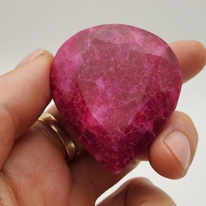 May include: A large, faceted, pink gemstone with a teardrop shape.