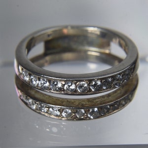 May include: A silver ring with a band of small clear stones.