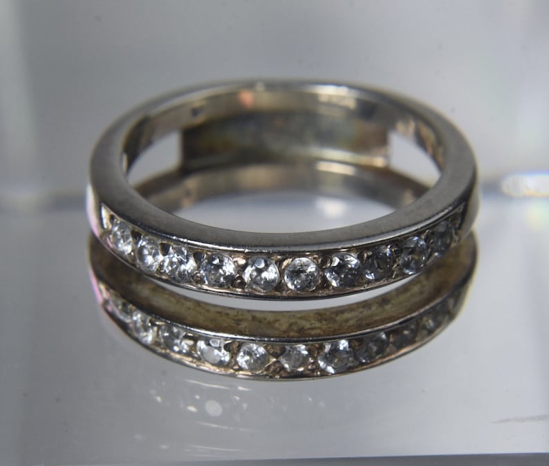 May include: A silver ring with a band of small clear stones.