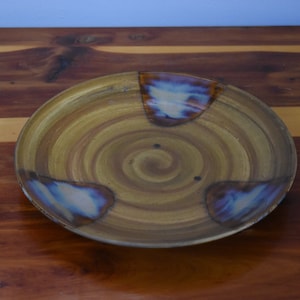 May include: A brown ceramic plate with a spiral design and three blue and white accents.