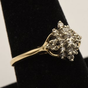 May include: A gold ring with a cluster of small diamonds set in a flower-like design.