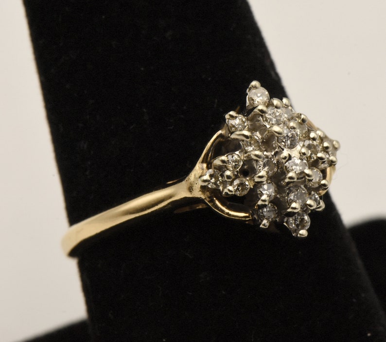 May include: A gold ring with a cluster of small diamonds set in a flower-like design.