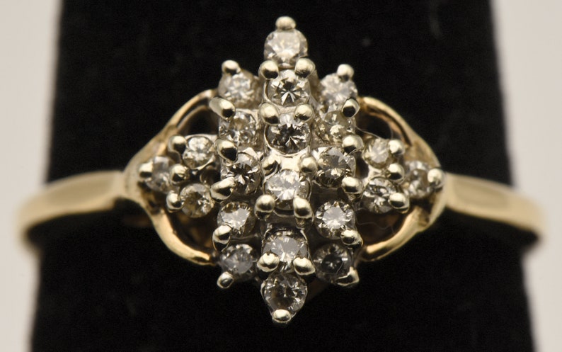 May include: A gold ring with a cluster of small diamonds set in a starburst pattern.