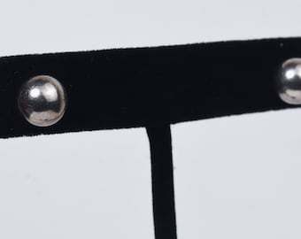 Op de afbeelding: Een paar zilveren oorbel studs met ronde, gladde oppervlakken. De oorbellen worden gepresenteerd op een zwarte fluwelen standaard.