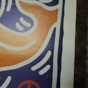 Puede incluir: Primer plano de una impresi&oacute;n de arte abstracto colorida con colores naranja, blanco y azul. La impresi&oacute;n presenta un s&iacute;mbolo de paz en la esquina inferior derecha.