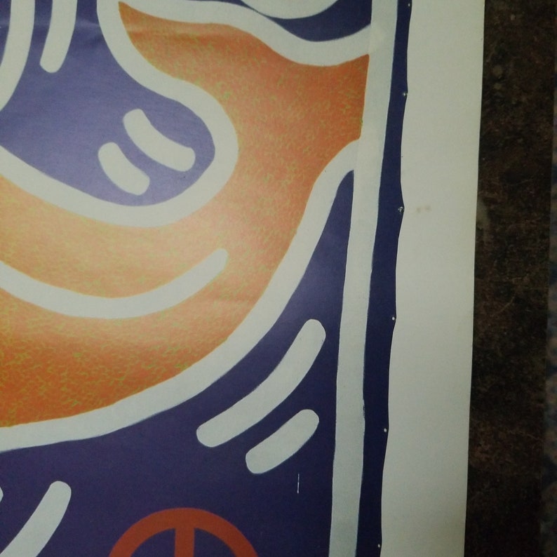 Puede incluir: Primer plano de una impresi&oacute;n de arte abstracto colorida con colores naranja, blanco y azul. La impresi&oacute;n presenta un s&iacute;mbolo de paz en la esquina inferior derecha.
