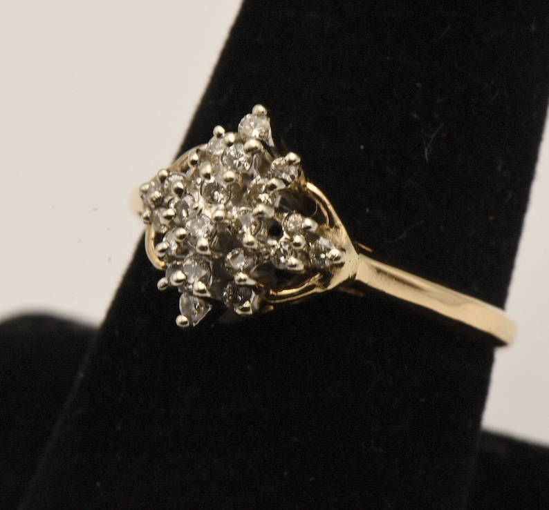 May include: A gold ring with a cluster of small diamonds set in a flower-like design.
