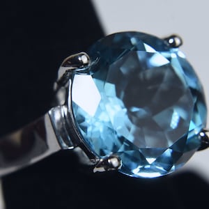 K&ouml;nnte beinhalten: Ein silberner Ring mit einem gro&szlig;en, runden, hellblauen Edelstein.