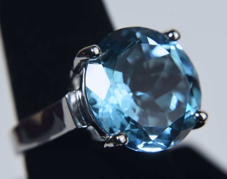 K&ouml;nnte beinhalten: Ein silberner Ring mit einem gro&szlig;en, runden, hellblauen Edelstein.