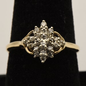 May include: A gold ring with a cluster of small diamonds set in a starburst design.