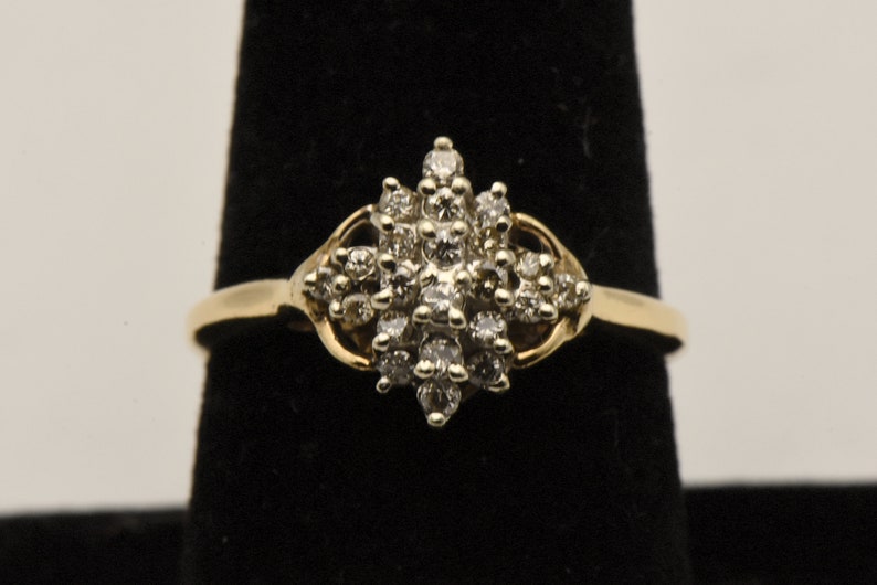 May include: A gold ring with a cluster of small diamonds set in a starburst design.