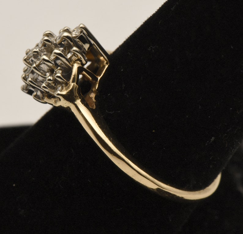 May include: A gold ring with a cluster of small diamonds set in a square shape.