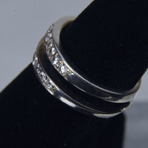 May include: Two silver rings with a row of small clear stones set into the band.