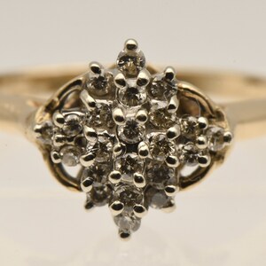 May include: A gold ring with a cluster of small diamonds set in a delicate, intricate design.