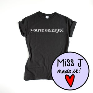 May include: Black t-shirt with the text "you're on mute." in silver lettering. A purple circle with the text "Miss J made it!" and a red heart is in the lower right corner.