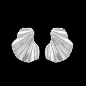 May include: A pair of silver-toned stud earrings featuring a fan-like, pleated design with a smooth, metallic finish. The earrings have an organic, wavy shape that mimics the appearance of a seashell or a folded fabric fan, set against a black background.