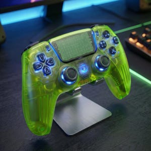 Peut inclure: Une manette de jeu vidéo vert néon transparent avec des lumières LED bleues, posée sur un support argenté. La manette comporte des boutons et des joysticks noirs, conçue pour le jeu.