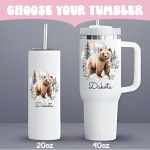 Pode incluir: Canecas brancas com um design de urso. Uma &eacute; uma caneca de 591 ml com canudo, e a outra &eacute; uma caneca de 1183 ml com al&ccedil;a. Ambas apresentam uma ilustra&ccedil;&atilde;o de urso em aquarela e o nome "Dakota".