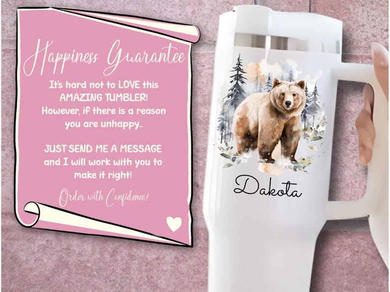 Pode incluir: Caneca branca com uma ilustra&ccedil;&atilde;o em aquarela de um urso pardo em um cen&aacute;rio de floresta, com o nome "Dakota" em escrita cursiva. Um pergaminho rosa com o texto "Happiness Guarantee" est&aacute; no fundo.