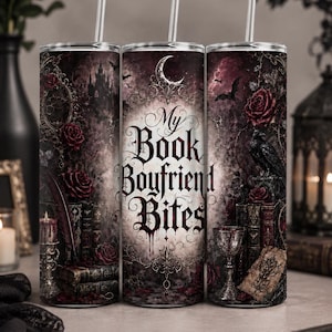May include: A cylindrical tumbler with a straw featuring a dark gothic design with red roses, a raven, old books, a candle, and a goblet. The text "My Book Boyfriend Bites" is printed in a stylized black font against a pale, moonlit background.