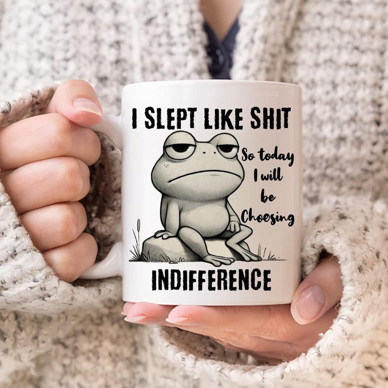 May include: White ceramic mug with a black and white illustration of a frog. The mug reads "I slept like shit so today I will be choosing indifference".