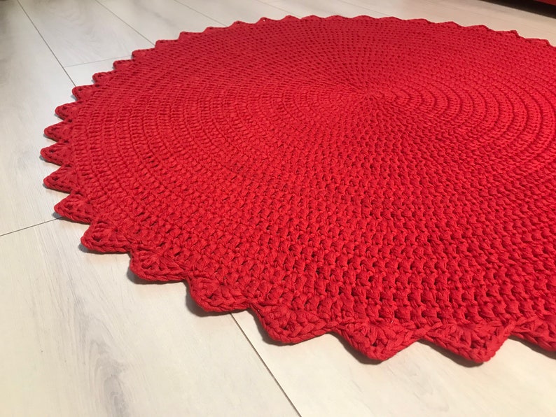May include: A red crocheted round rug with a scalloped edge.