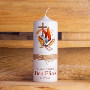 Könnte beinhalten: Weiße Kerze mit einem Motiv von Taube, Kelch und Kreuz. Die Kerze ist mit einer braunen Kordelschleife verziert und trägt den Text "Meine Firmung Ben Elias 11.05.2025".