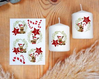 Puede incluir: Un juego de cuatro velas blancas con diseños navideños rojos y verdes. Cada vela tiene un número del 1 al 4 y una ilustración de un reno. Las velas se acompañan de una hoja de pegatinas con diseños similares.