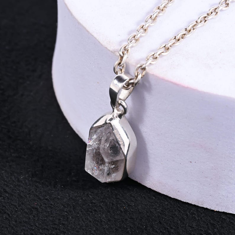 Pu&ograve; includere: Una collana d'argento con un pendente di cristallo trasparente. Il cristallo ha un aspetto naturale e grezzo con inclusioni interne. La catena &egrave; una delicata maglia d'argento. Il pendente &egrave; incastonato in una lunetta d'argento.
