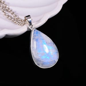 May include: A teardrop-shaped pendant necklace featuring a large, iridescent moonstone. The moonstone has a pearlescent, blue and white glow, set in a silver-colored metal. The chain is also silver-colored and delicate. The necklace is displayed against a white background.