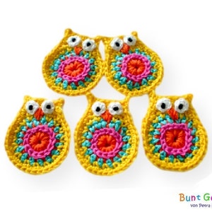 Pode incluir: Cinco enfeites de coruja de crochê em amarelo, rosa, laranja, azul e turquesa. Cada coruja tem um centro redondo e colorido e olhos brancos.