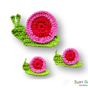 Può includere: Tre lumache all'uncinetto di diverse dimensioni. La lumaca più grande è verde con un guscio rosa e rosso. La lumaca media è verde con un guscio rosa e rosso. La lumaca più piccola è verde con un guscio rosa e rosso.