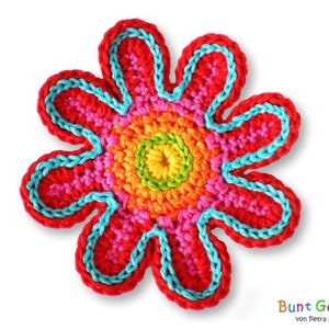 Könnte beinhalten: Eine handgefertigte Häkelblume mit einem farbenfrohen Design. Die Blume hat eine rote Außenschicht, einen hellblauen Rand und eine Mitte mit Rosa-, Orange-, Gelb- und Grüntönen. Der Text "Bunt Gehäkelt" ist sichtbar.