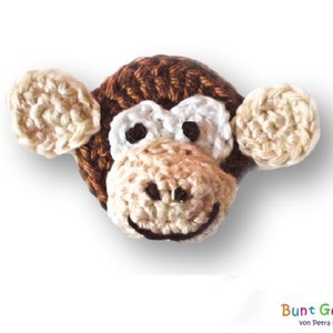 May include: A crocheted monkey toy with brown fur, white eyes, and a beige face. The monkey has beige ears and a brown nose.